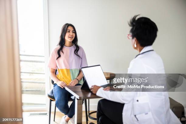 doctor consulting with teenage girl in exam room - daily life in multicultural birmingham stock pictures, royalty-free photos & images