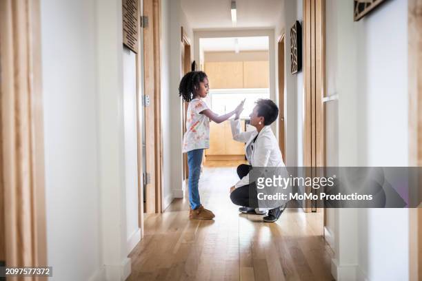 female doctor high fiving with young girl in medical office hallway - daily life in multicultural birmingham stock pictures, royalty-free photos & images