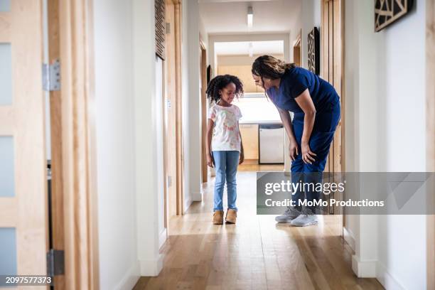female nurse talking with young girl in medical office hallway - hand on knee stock pictures, royalty-free photos & images