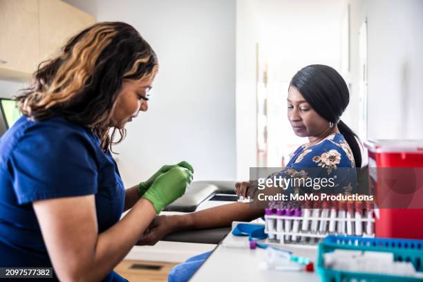 female nurse drawing blood sample from woman in medical office - reportage hospital stock pictures, royalty-free photos & images