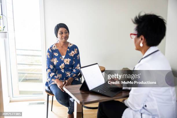 doctor consulting with woman in exam room - daily life in multicultural birmingham stock pictures, royalty-free photos & images