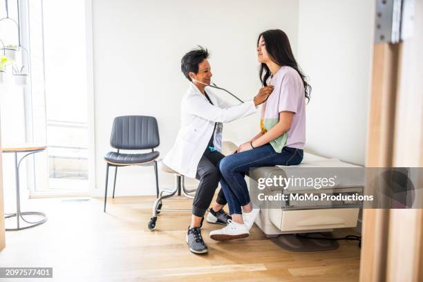 doctor listening to teenage girls heart with stethoscope - doctor stethoscope patient whole body stock pictures, royalty-free photos & images