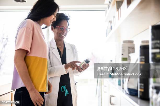 female doctor discussing supplements with teenage girl in medical office - daily life in multicultural birmingham stock pictures, royalty-free photos & images