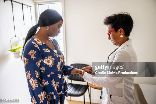 doctor performing joint exam on woman in exam room - daily life in multicultural birmingham stock pictures, royalty-free photos & images