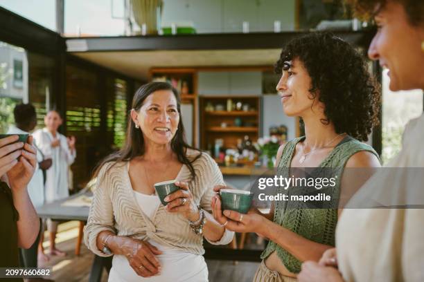 smiling group of women talking over tea during a wellness retreat together - women sipping drink stock pictures, royalty-free photos & images