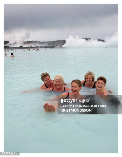 Five Icelandic young women smile while they take a bath on October 13, 2008 in the Blue Lagoon spa located in a lava field in Grindavík on the...