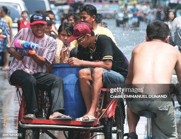 Young Thais roam down a street of Bangkok soaking people atop at tricycle transformed for the day into a "water battle tank" 12 April as part of the...