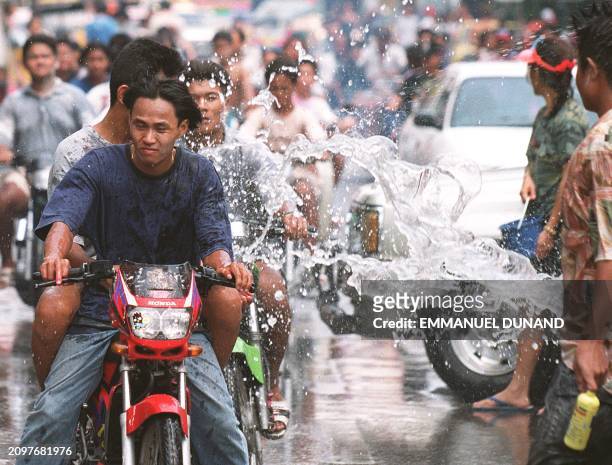 Group of motorcyclists get friendly hosing down with water whilst driving through a street in the capital 13 April during celebrations for Songkran,...