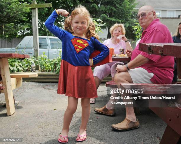 Rachel Dubec dressed as Super Girl, gives her strong girl pose as her grandparents, Joyce and Ron Lanoue, up visiting from Florida, look on outside...