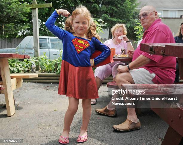 Rachel Dubec dressed as Super Girl, gives her strong girl pose as her grandparents, Joyce and Ron Lanoue, up visiting from Florida, look on outside...