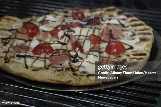 Garlic and herb pizza dough with cherry tomatoes, three cheeses, prosciutto and drizzled with balsamic vinegar fig glaze at the very end cooks on a...