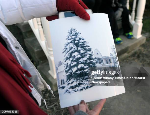 Nancy Winkler shows a photograph of a tree in their front yard from a past winter as workers from New York State OGS and DOT and workers with Donovan...