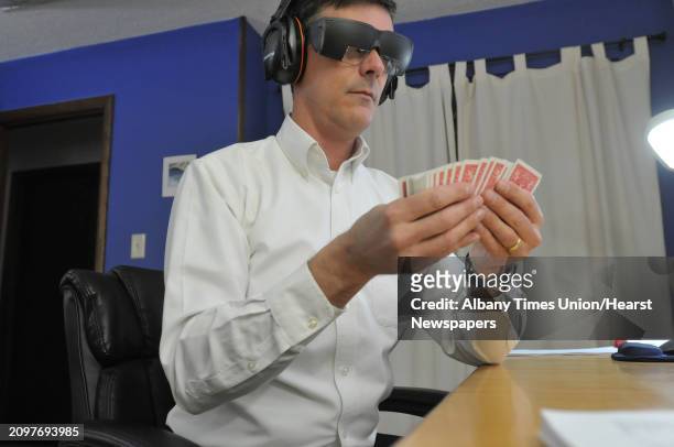 Brad Zupp goes through a deck of cards to memorize them on Tuesday, Dec. 17, 2013 in Wilton, NY. Zupp wears ear protection headphones and glasses he...