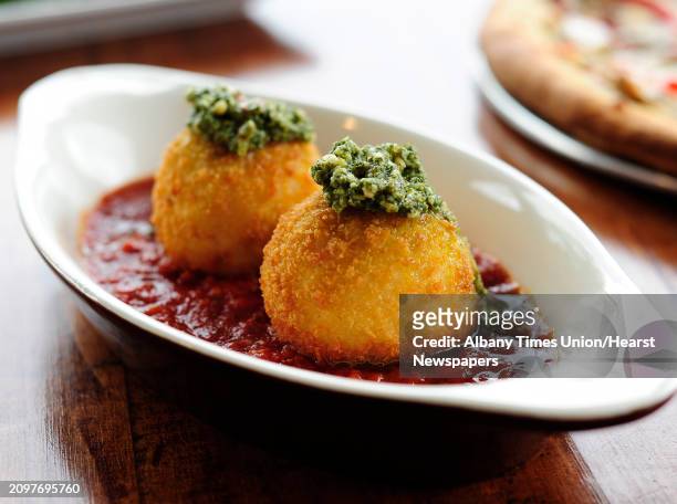 View of a plate of arancini, which are risotto balls stuffed with cheese and topped with pesto, photographed at Villago Pizzeria & Ristorante on...