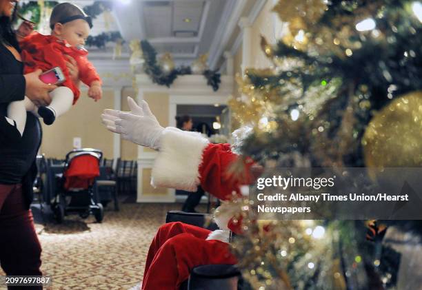 Emily Roth, eight months old, from Niskayuna, is handed over to Santa to get her photo taken during the Brunch with Santa event at Angelo's Tavolo at...