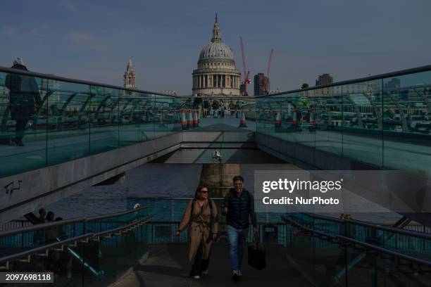 People are walking on the Millennium Bridge with the backdrop of St. Paul's Cathedral in London, England, on March 21, 2024.