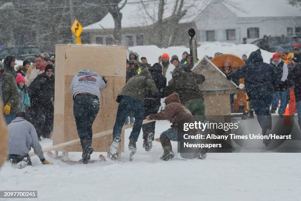 Two teams race towards the finish line as one team's outhouse sled starts to come apart on Lake Desolation during the annual Outhouse Races at...