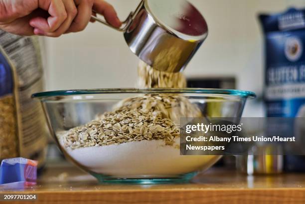 Emily Masters adds oats to the bowl as she makes gluten free brown sugar oatmeal cookies on Monday, April 1 in Albany, N.Y.