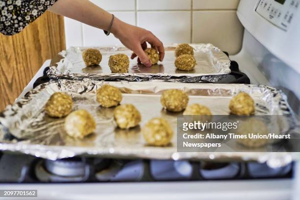 Emily Masters rolls the batter into balls and then places them on a cookie sheet for baking as she makes gluten free brown sugar oatmeal cookies on...