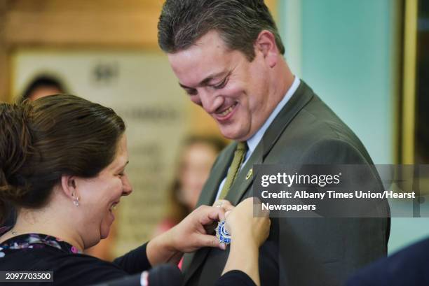 Alethea Johnston pins the badge on her husband, Jason Johnston, a Cohoes Police Detective Lieutenant during a promotions and swearing-in ceremony at...