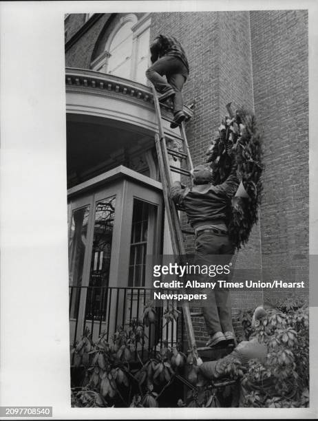 Fort Orange Club, Washington Avenue, Albany, New York - Paul Meister climbs ladder to accept the wreath that will adorn the front of the Fort Orange...