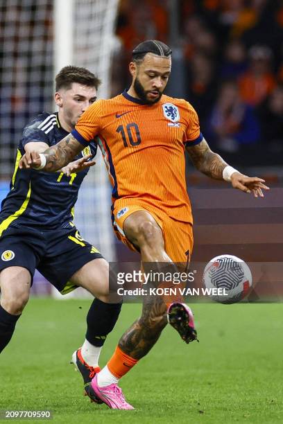 Netherlands' forward Memphis Depay passes the ball under pressure from Scotland's midfielder Billy Gilmour during the international friendly football...