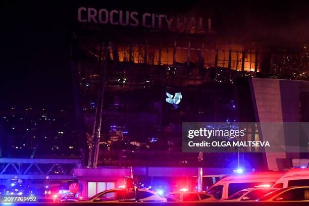 Emergency services vehicles are seen outside the burning Crocus City Hall concert hall following the shooting incident in Krasnogorsk, outside...