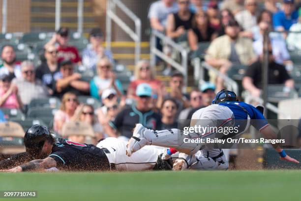 Andrew Knapp of the Texas Rangers tags Jose Herrera of the Arizona Diamondbacks out at home in the fourth inning during a spring training game...