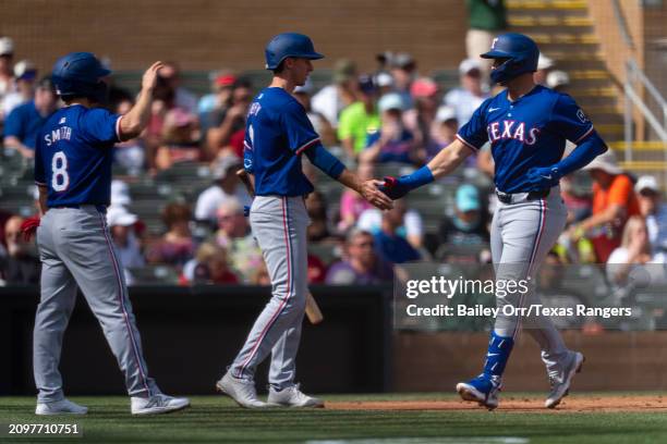 Andrew Knizner of the Texas Rangers celebrates with Matt Duffy and Josh Smith after hitting a three-run home run in the second inning during a spring...