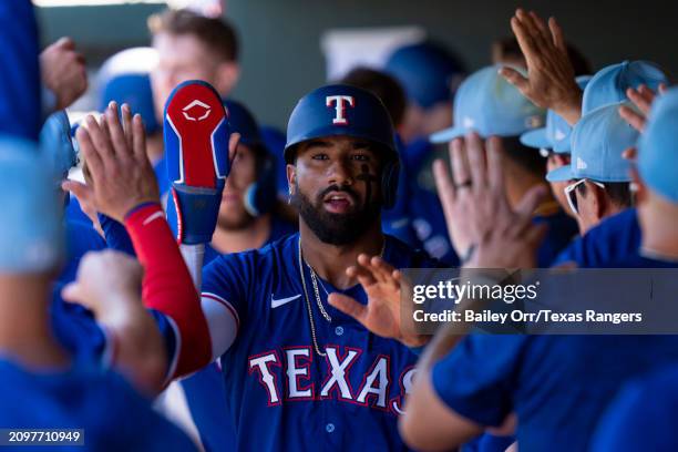 Ezequiel Duran of the Texas Rangers celebrates with teammates in the dugout after scoring in the second inning during a spring training game against...