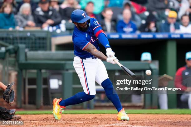 Adolis Garcia of the Texas Rangers hits an RBI-double during a spring training game against the Arizona Diamondbacks at Surprise Stadium on March 07,...