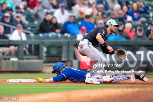 Josh Hatcher of the Texas Rangers slides into third base after hitting a two-run triple in the fifth inning during a spring training game against the...