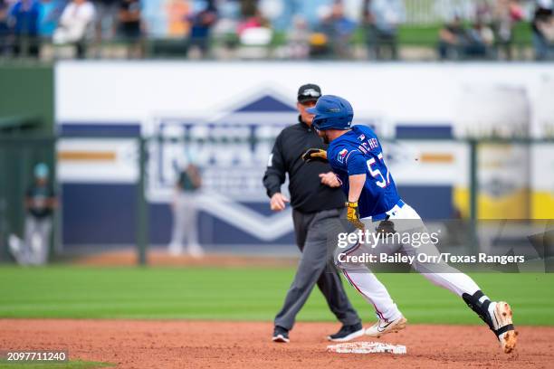 Josh Hatcher of the Texas Rangers rounds the bases after hitting a two-run triple in the fifth inning during a spring training game against the...