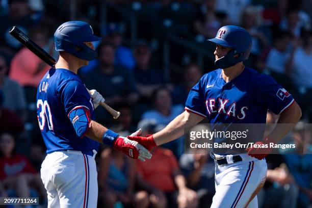 Wyatt Langford celebrates with Nathaniel Lowe of the Texas Rangers after hitting a two-run home run in the third inning during a spring training game...