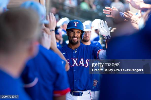 Marcus Semien of the Texas Rangers celebrates with teammates in the dugout after hitting a solo home run in the third inning during a spring training...