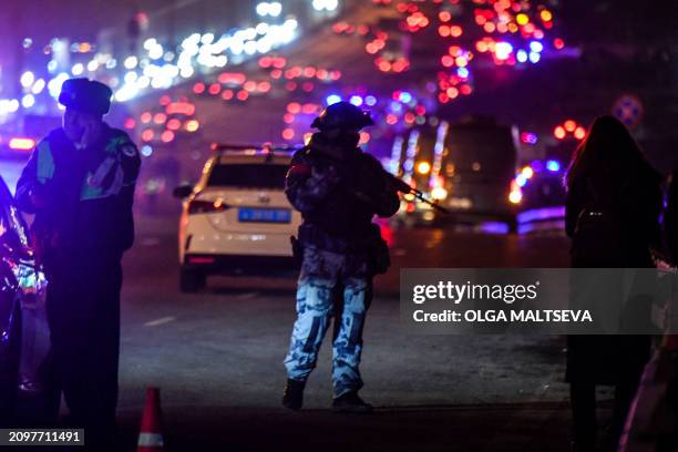 Law enforcement officer stands guard outside the burning Crocus City Hall concert hall following the shooting incident in Krasnogorsk, outside...