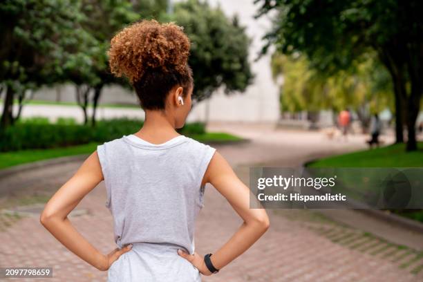 vista trasera de una mujer haciendo ejercicio en un parque público y escuchando música - hispanolistic fotografías e imágenes de stock