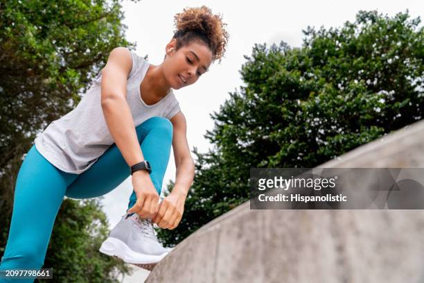 female jogger tying her shoes at the park before going for a run - hispanolistic stockfoto's en -beelden
