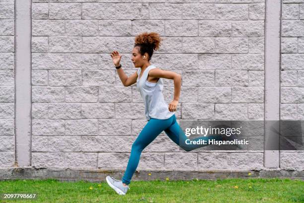 woman running outdoors and listening to music - hispanolistic stockfoto's en -beelden