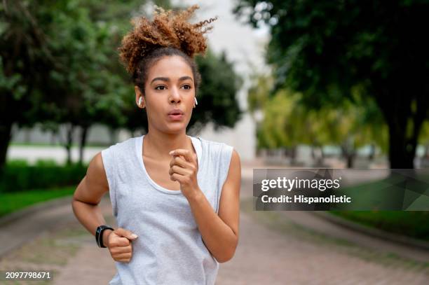woman running outdoors and listening to music - hispanolistic stockfoto's en -beelden