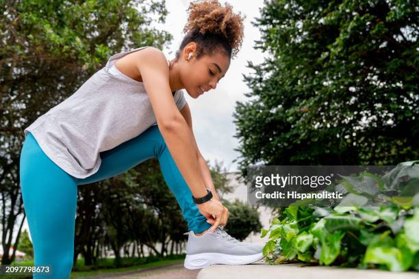 female runner exercising at the park and tying her shoes - hispanolistic stockfoto's en -beelden