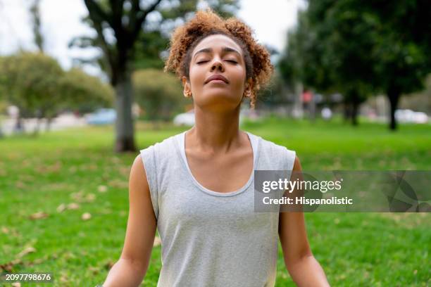 mujer meditando al aire libre en el parque - hispanolistic fotografías e imágenes de stock