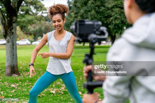 athletic woman making a fitness class tutorial at the park - hispanolistic stockfoto's en -beelden