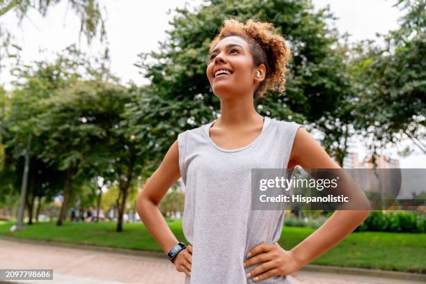 happy female runner smiling at the park - hispanolistic stockfoto's en -beelden