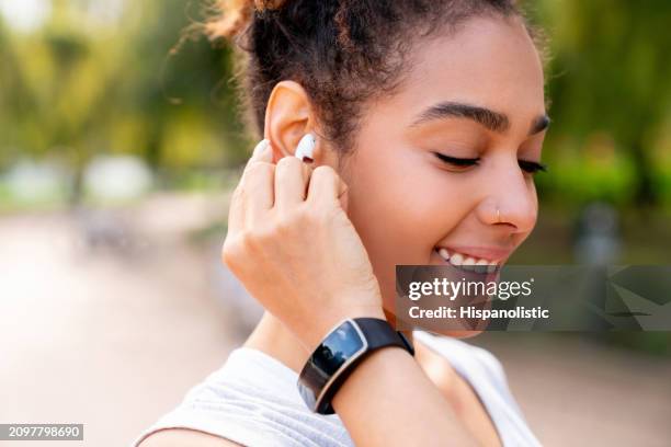 woman running outdoors using a fitness tracker and headphones - hispanolistic stockfoto's en -beelden