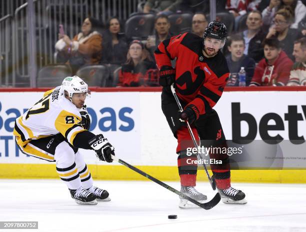 Brendan Smith of the New Jersey Devils clears the puck as Sidney Crosby of the Pittsburgh Penguins defends during the first period at Prudential...