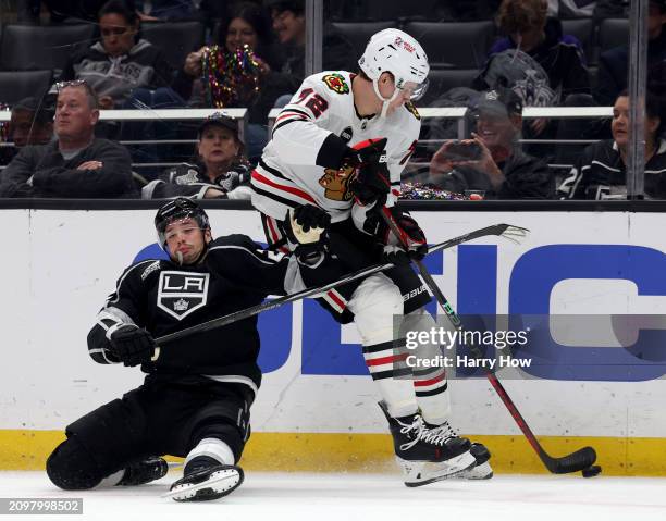 Kevin Fiala of the Los Angeles Kings loses his balance as he checks Alex Vlasic of the Chicago Blackhawks during the first period at Crypto.com Arena...