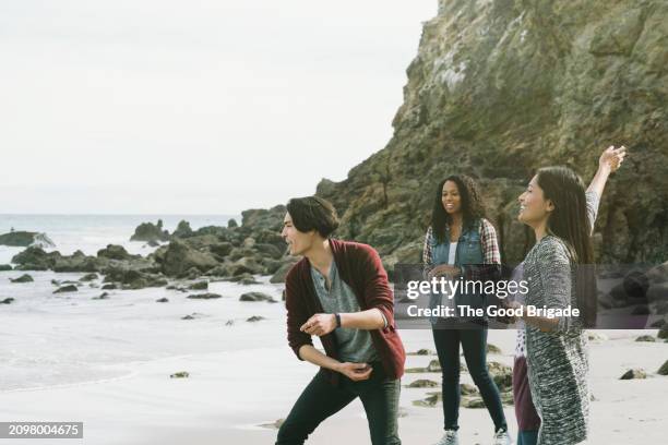 happy young friends skimming rocks at beach - malibu nature stock pictures, royalty-free photos & images