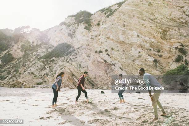 young male and female friends playing soccer at beach - malibu nature stock pictures, royalty-free photos & images