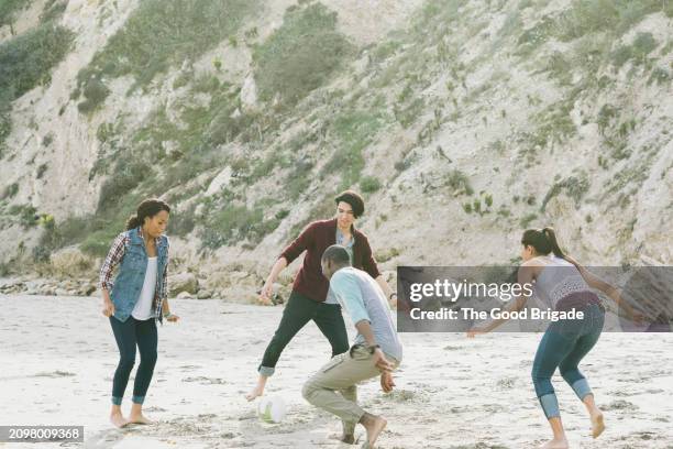 friends playing soccer on beach - kicking sand stock pictures, royalty-free photos & images